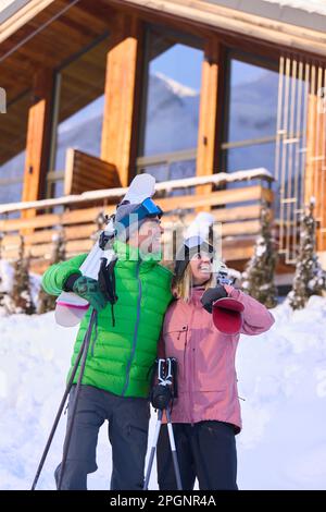 Glücklicher Mann und glückliche Frau stehen mit Skiern im Schnee Stockfoto