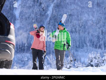 Mann und Frau laufen mit Skiern und Stöcken vor dem Berg Stockfoto