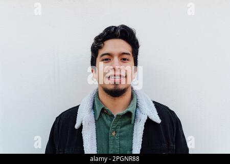 Lächelnder junger Mann, der vor der Wand steht Stockfoto