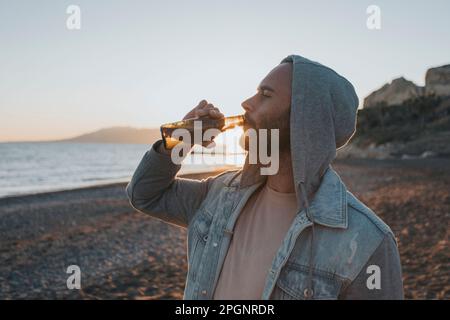 Ein Mann trinkt Bier am Strand Stockfoto