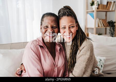 Glückliche Tochter, die zu Hause mit ihrer Mutter auf dem Sofa sitzt Stockfoto