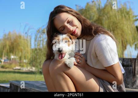 Junge Frau, die mit dem Hund im Park sitzt Stockfoto