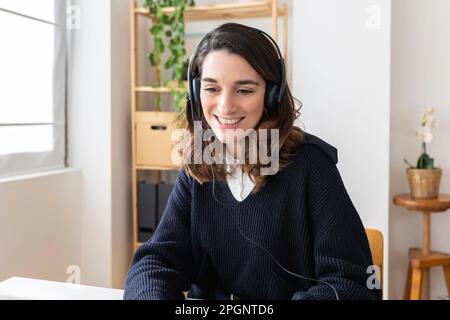 Glückliche Geschäftsfrau, die ein Headset trägt und am Schreibtisch sitzt Stockfoto