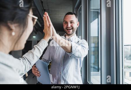 Ein glücklicher Geschäftsmann, der einem Kollegen im Amt High Five gibt Stockfoto