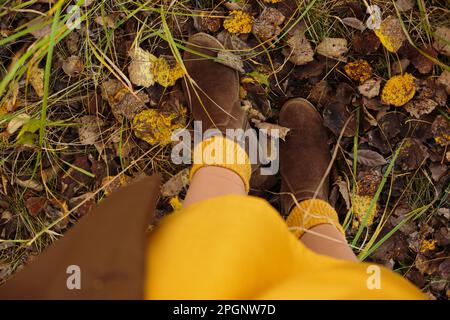 Eine Frau in Stiefeln, die auf gefallenen Blättern steht Stockfoto