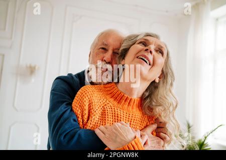 Glückliches Seniorenpaar, das sich zu Hause umarmt Stockfoto