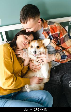 Ein junges Paar, das zu Hause mit Pembroke Welsh Corgi spielt Stockfoto