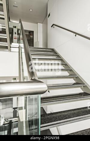 Edelstahltreppen, gehärtetes Glas und Stufen aus poliertem schwarzem Granit in einem Bürogebäude Stockfoto