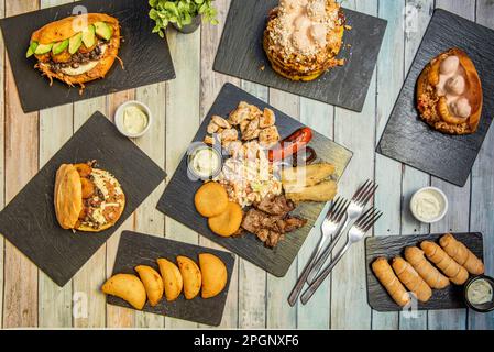 Venezolanisches Speisenangebot mit Empanadillas, einem Consumado plato, tequeños, Areas mit verschiedenen Füllungen auf Schiefertellern Stockfoto