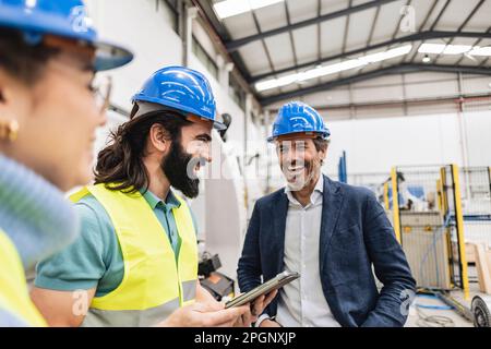 Zufriedener Ingenieur mit Kollegen in der Fabrik Stockfoto