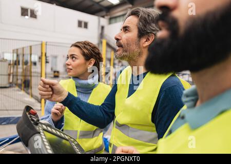 Ingenieur, der die Schalttafel hält und mit Kollegen im Werk zusammenarbeitet Stockfoto