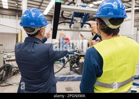 Techniker tragen Schutzhelm, um Maschinenteile zu untersuchen Stockfoto