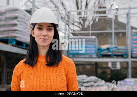 Selbstbewusste Frau trägt Schutzhelm auf der Baustelle Stockfoto