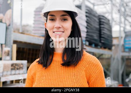 Lächelnde Frau mit Schutzhelm auf der Baustelle Stockfoto