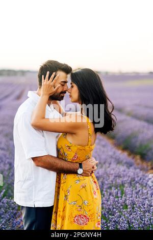 Junge Frau umarmt Mann im Feld Stockfoto
