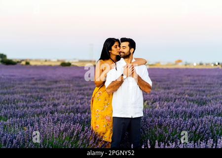 Junge Frau umarmt den Mann im Lavendelfeld unter dem Himmel Stockfoto