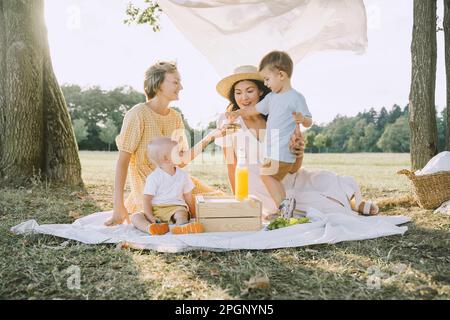 Glückliche Frauen genießen ein Picknick mit Söhnen im Park Stockfoto