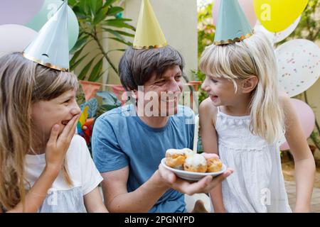 Glücklicher Vater, der den Geburtstag seiner Tochter im Garten feiert Stockfoto