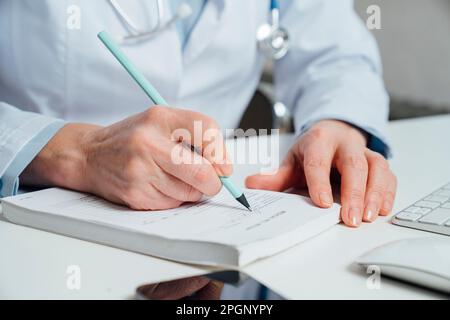 Arzt schreibt Rezept mit Stift am Schreibtisch Stockfoto