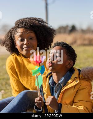 Ein Junge bläst mit Mutter im Park an einem sonnigen Tag Stockfoto