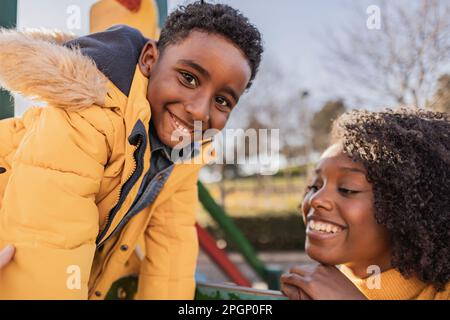 Glückliche Mutter und Sohn, die Spaß auf dem Spielplatz haben Stockfoto
