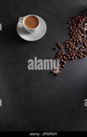 Tasse Espresso und geröstete Kaffeebohnen auf schwarzem Hintergrund Stockfoto