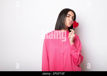 Junge Frau mit herzförmigem Lutscher Stockfoto