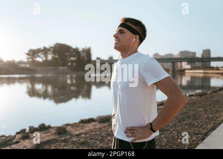 Ein glücklicher Mann mit Händen in der Hüfte, der am See steht Stockfoto