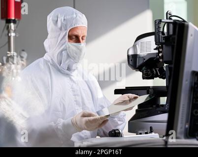 Wissenschaftler tragen Schutzanzug und untersuchen Wafer-Chip im Labor Stockfoto