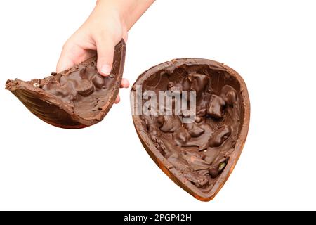 Ein Kind, das die Hälfte des dunklen Schokoladen-Ostereis mit knusprigen Mandeln mitnimmt. Stockfoto