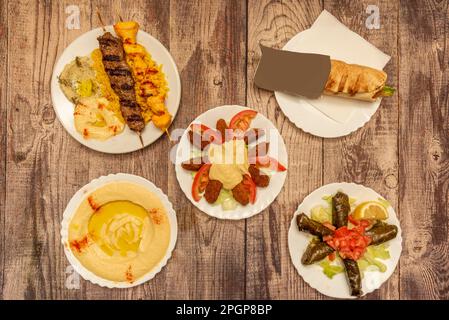 Auswahl an großartigen arabischen und nahöstlichen Gerichten mit Weinsarma, Schawarma, gegrillten Fleischspießen, Hummus mit Öl und Paprika, Falafel mit Salat Stockfoto