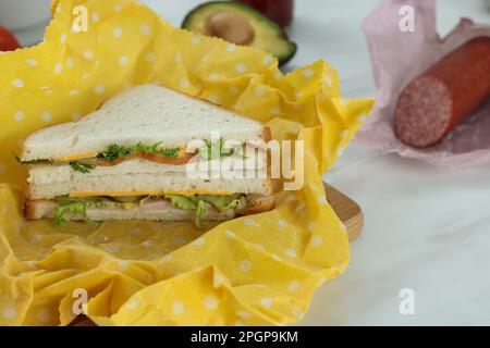 Leckeres Sandwich in Bienenwachs auf einem weißen Marmortisch Stockfoto