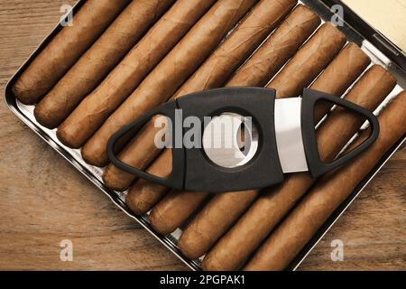 Humidor mit Zigarren und Schneidevorrichtung auf Holztisch, Draufsicht Stockfoto