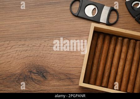 Box mit Zigarren und Schneidezähnen auf Holztisch, flach liegend. Platz für Text Stockfoto
