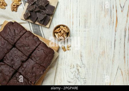 Köstliche frisch gebackene Brownies, Walnüsse und Schokoladenstücke auf einem weißen Holztisch, flach liegend. Platz für Text Stockfoto