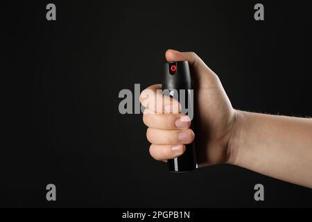 Ein Mann mit Pfefferspray auf schwarzem Hintergrund, Nahaufnahme. Platz für Text Stockfoto