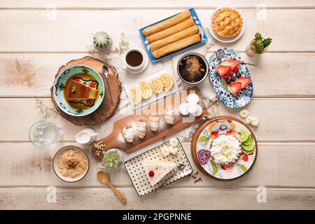 Verschiedene peruanische Gebäckstücke Desserts Buffet Tisch Brunch süße Speisen auf einem weißen Holztisch Stockfoto