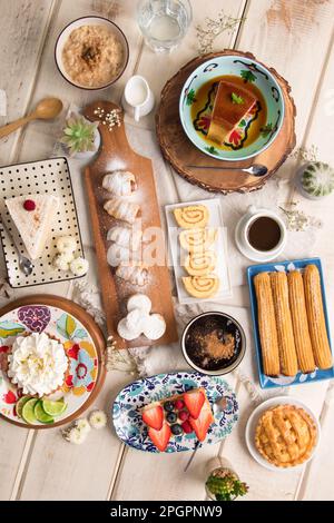 Verschiedene peruanische Gebäckstücke Desserts Buffet Tisch Brunch süße Speisen auf einem weißen Holztisch Stockfoto