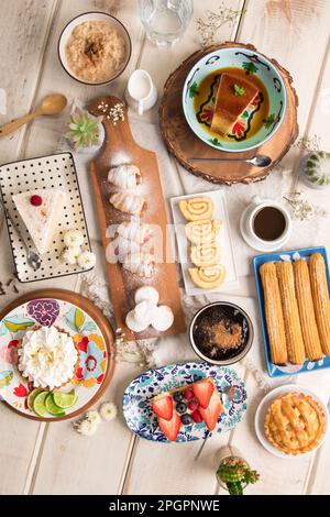 Verschiedene peruanische Gebäckstücke Desserts Buffet Tisch Brunch süße Speisen auf einem weißen Holztisch Stockfoto