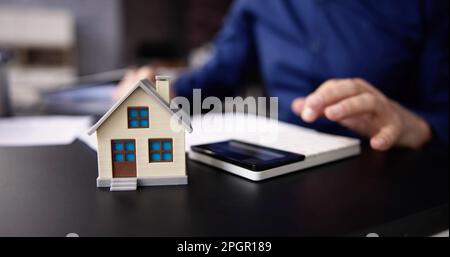Person Hand Tun Immobilien Steuerberechnung Mit Rechner Des Hauses Modell Stockfoto