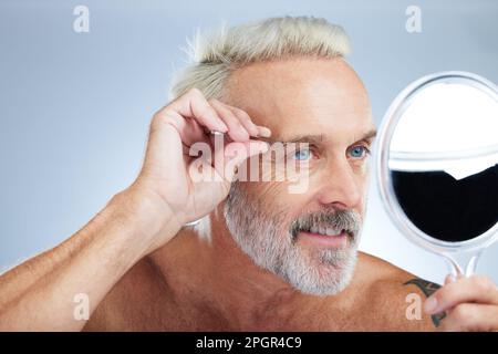 Seniorenmann, Pinzette und Spiegel in einem Studio, das Haare reinigt und pflegt. Wellness, Dermatologie und Schönheitsroutine eines reifen männlichen Modells Stockfoto