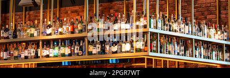 Die Flaschen mit Alkohol und Spirituosen in Regalen mit Hintergrundbeleuchtung in einem Pub oder einer Bar. Stockfoto