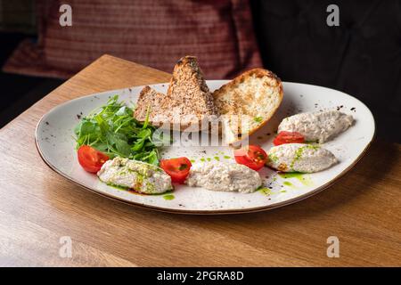 Kabeljauleberpastete mit braunem Brot auf dem Teller. Hausgemachtes Brot aus Kabeljauleber und Hüttenkäse. Gesundes Essen Stockfoto