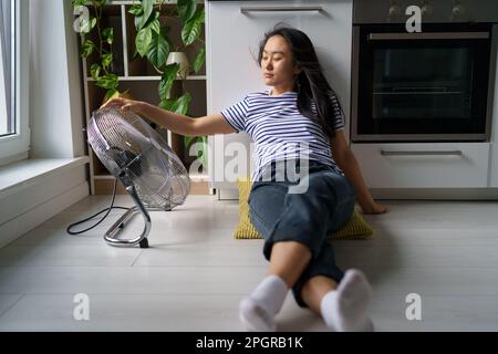 Müde, überhitzte, junge Asiatin, die zu Hause an Hitze leidet Stockfoto