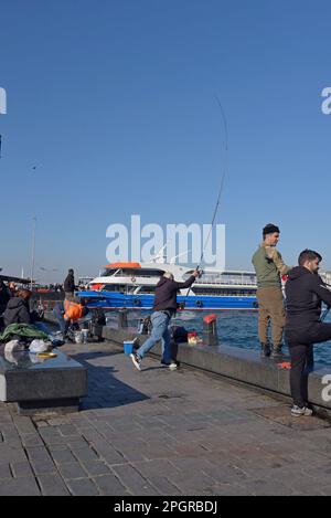 Ein Fischer, der seine Leine auf die Mauer des Goldenen Horns in Eminönü Sahil, Istanbul, Türkei wirft Stockfoto