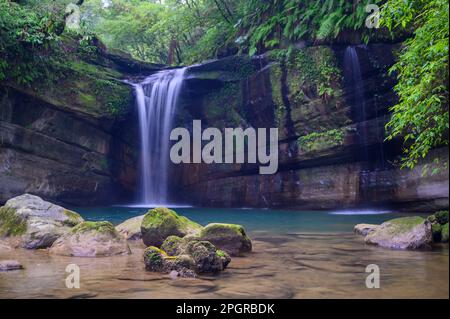 Hinter den moosbedeckten Felsen und grünen Bäumen befindet sich der Wanggu-Wasserfall. Der geheime Ort im Bergwald, der See ist traumhaft smaragdgrün. Pingxi, Neu-Taipeh Stockfoto