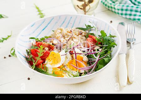 Haferbrei zum Frühstück mit gekochten Eiern, Tomaten und roten Zwiebeln. Gesunde ausgewogene Ernährung. Trendiges Essen. Stockfoto
