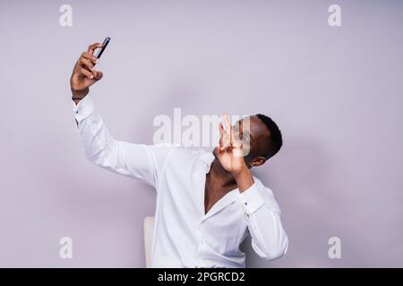 Attraktiver junger afrikanischer Geschäftsmann mit einem Handy isoliert vor grauem Hintergrund Stockfoto