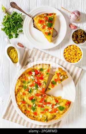 Vegetarisches Green Chile Enchilada Kasserole aus Maistortillas mit gekühlten Bohnen, Mais, Sauce und Käse, garniert mit Pico de gallo, vertikal Stockfoto