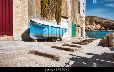 Eine Slipway zu einer Bucht in einem mediterranen Fischerdorf, mit Holzblöcken auf dem Boden für die Fischerboote Stockfoto